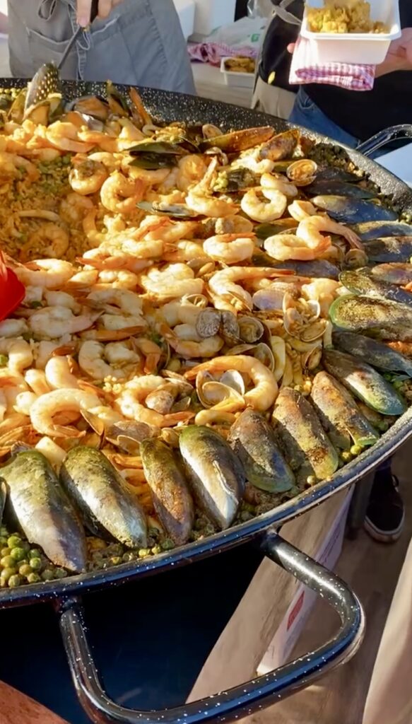 A person serving giant paella to customers at Mindil Beach Sunset Markets in Darwin. 