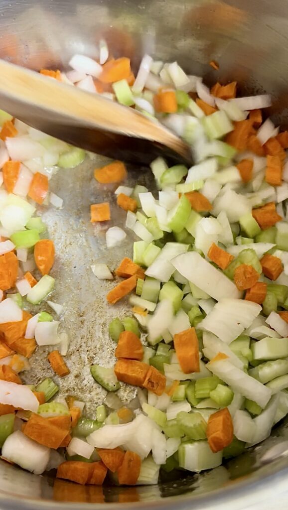 Sautéing diced onions, carrots, and celery in a pot for a soup base
