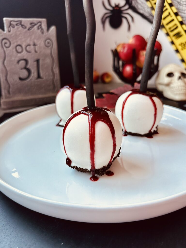 Gothic Bleeding White Chocolate Candy Apples - Final Presentation Gothic white chocolate bleeding candy apples on a dark Halloween dessert table by Bacon and Spice