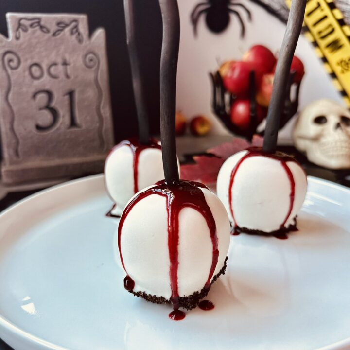 Bleeding Gothic white chocolate candy apples on a dark Halloween dessert table