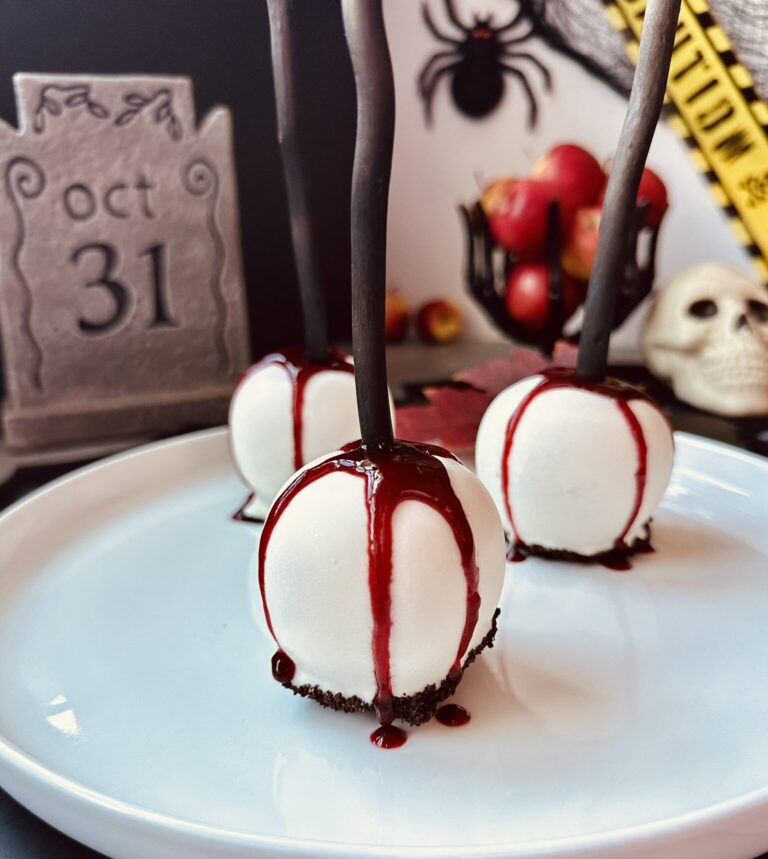 Bleeding Gothic white chocolate candy apples on a dark Halloween dessert table