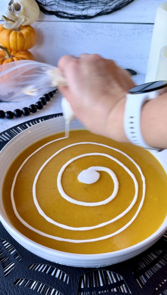 A complete clockwise concentric ring spiral of heavy cream piped on top of butternut squash soup.